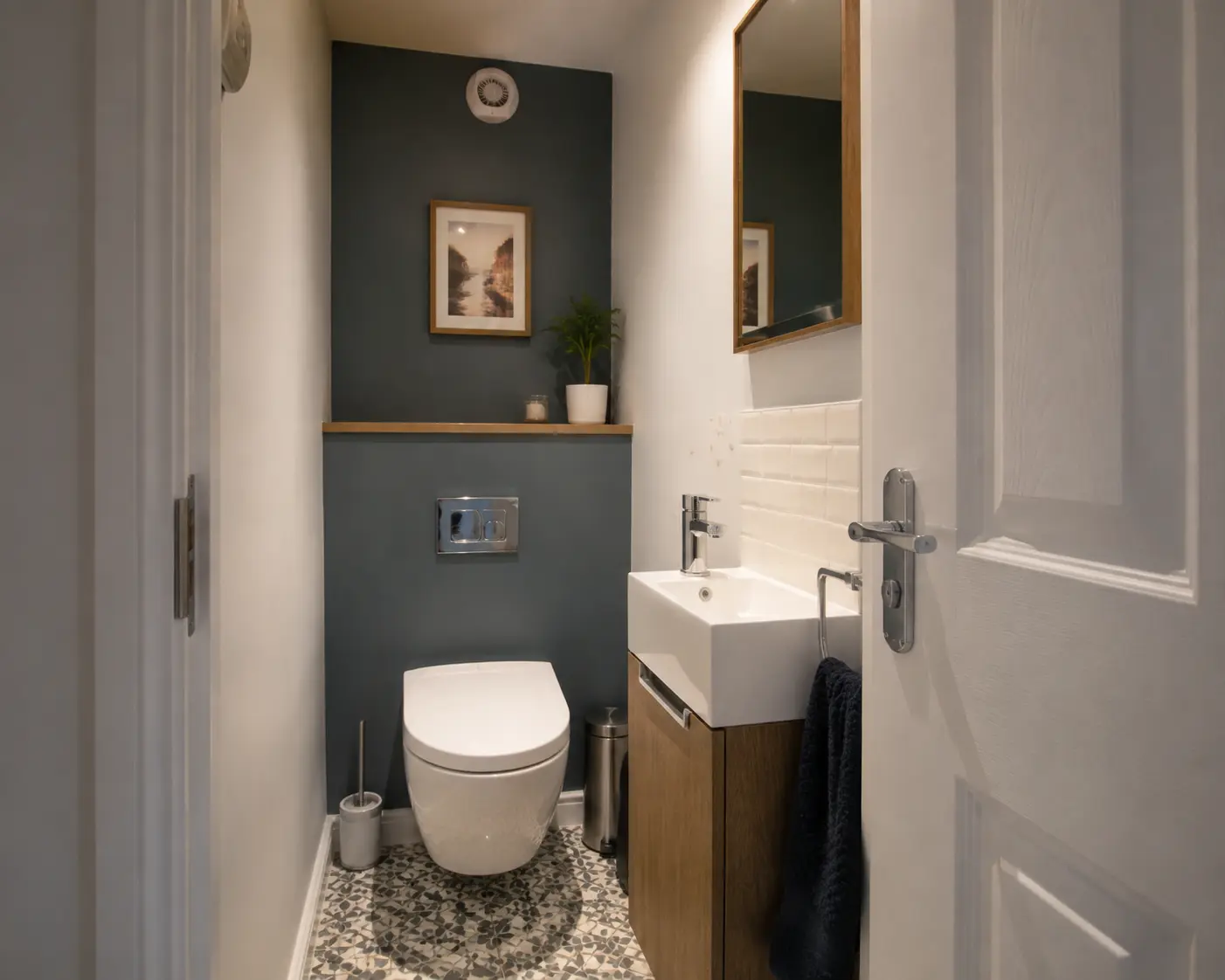 Compact British downstairs toilet with a slim vanity and patterned floor