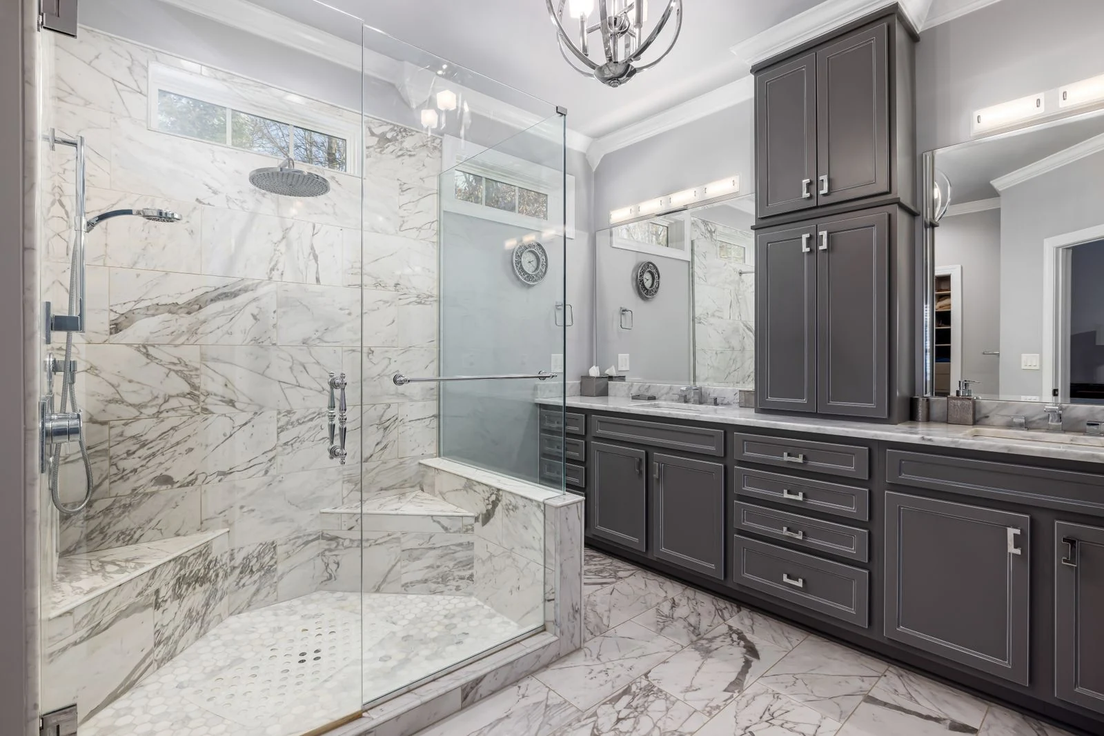Spacious bathroom featuring elegant marble shower and dark cabinetry