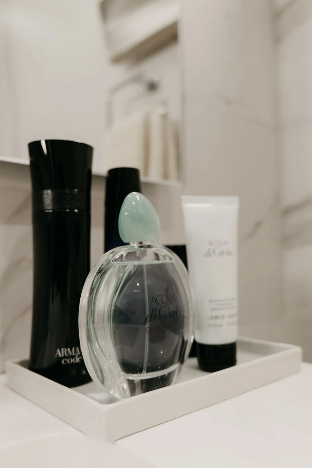 Sophisticated selection of luxury perfumes and body care products on a white tray