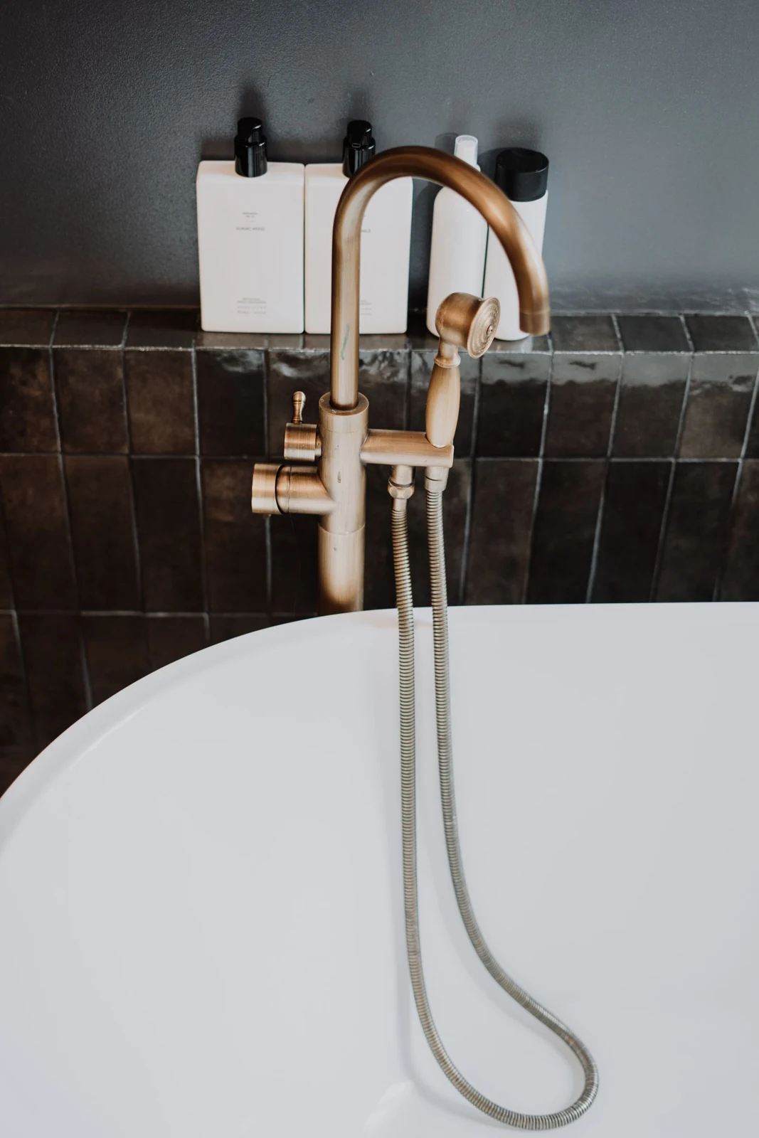 Elegant bathroom featuring a gold faucet and modern accessories on a dark tile background
