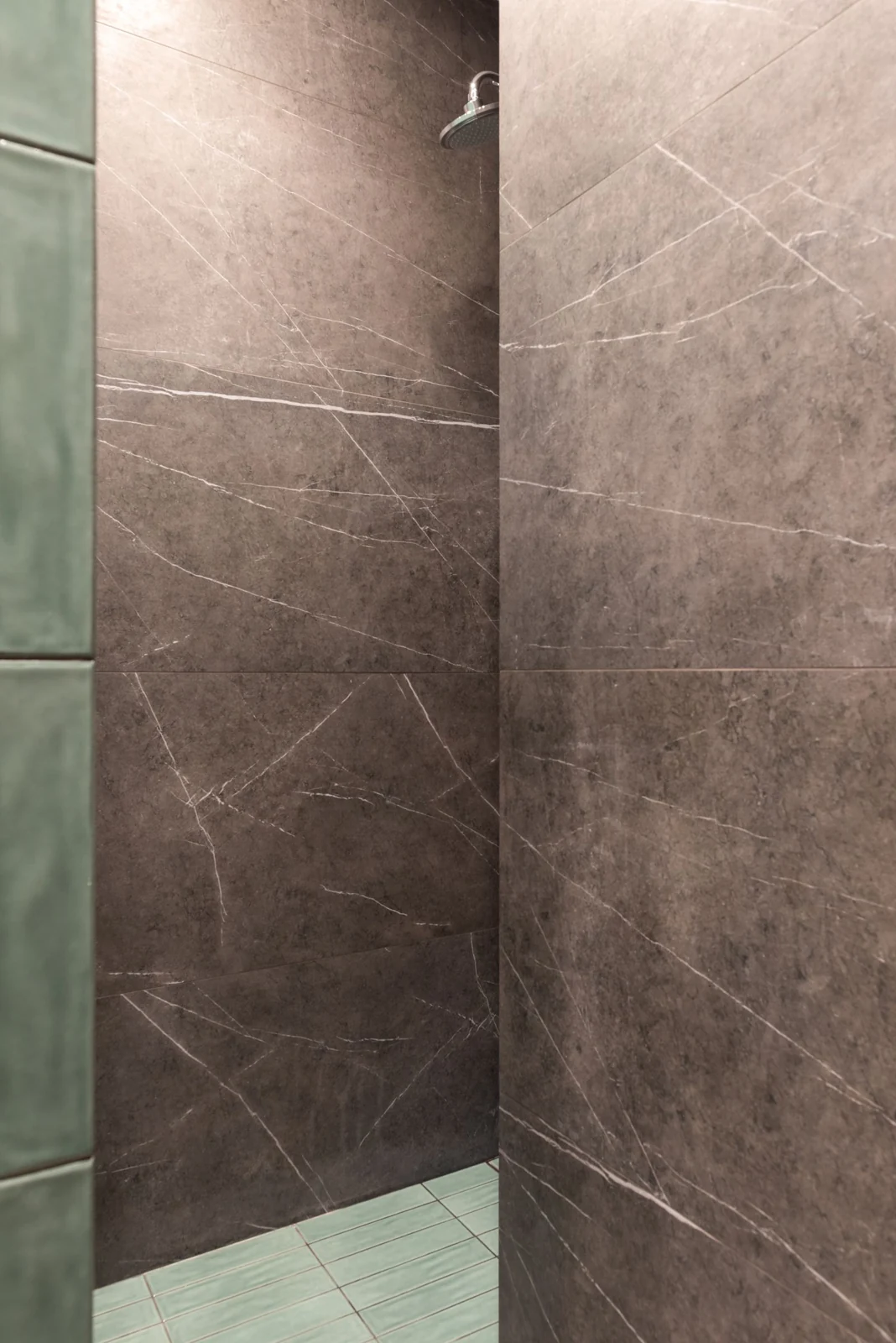 Modern shower room with marble walls and green tiling, showcasing a sleek design