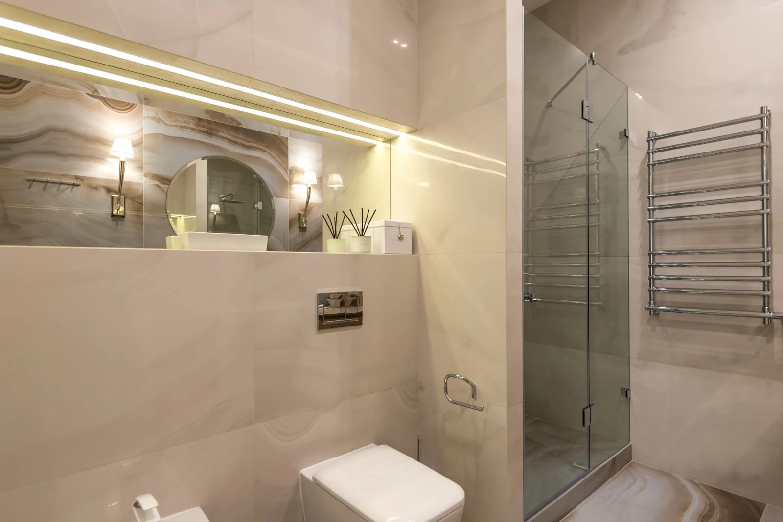 A contemporary bathroom with marble tiles, glass shower, and LED lighting